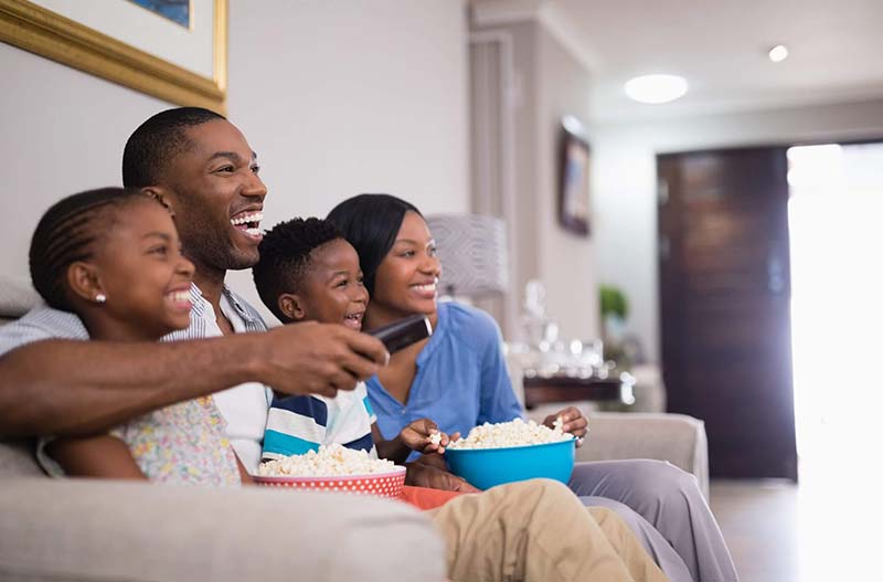 Cheerful african american family having popcorn while watching television