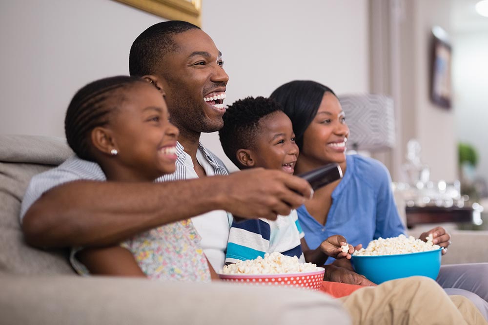 Cheerful african american family having popcorn while watching television